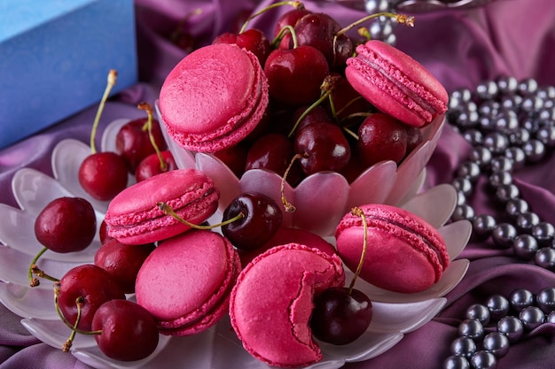 a bowl of cherries next to a bowl of pink macarons