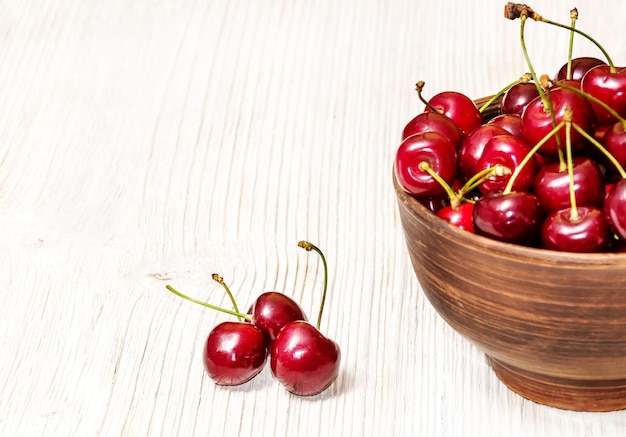 Bowl of cherries on white wooden background