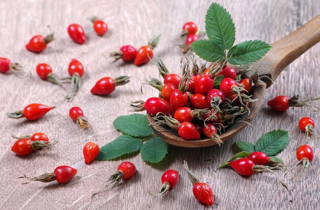 a bowl of cherries with leaves and berries on a wooden background.