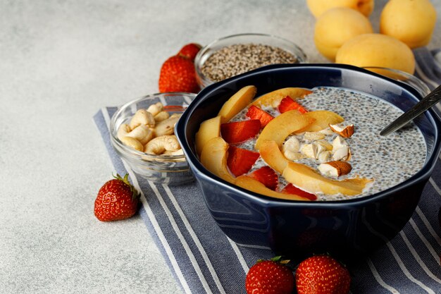 Bowl of chia poudding with pieces of apricots and strawberry