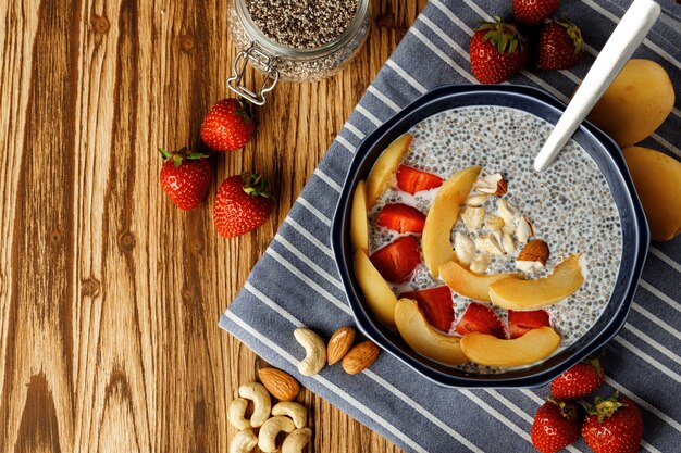 Bowl of chia poudding with pieces of apricots and strawberry