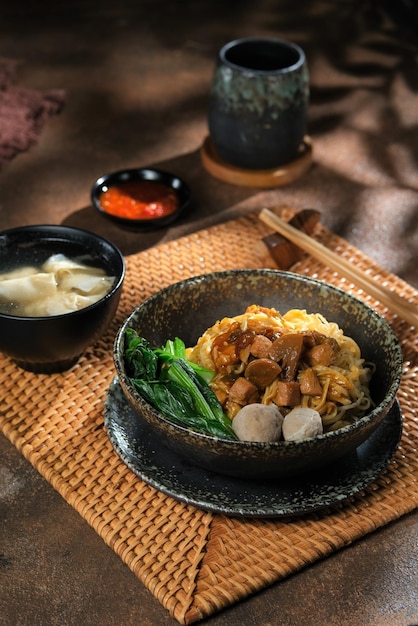 A bowl of Chicken noodles in black rustic bowl Mie ayam