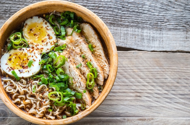 Bowl of chicken ramen soup on wooden table