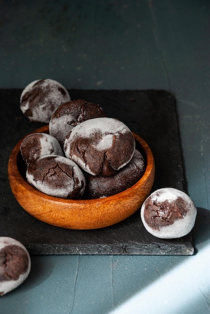 A bowl of chocolate donuts with powdered sugar on top