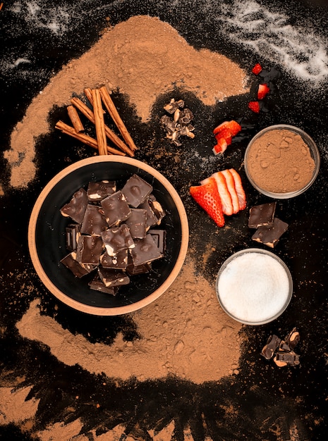 Bowl of chocolate pieces bowl of sugar and cocoa with pieces of strawberries and cinnamon