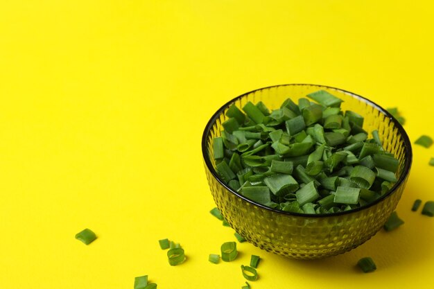 Bowl of chopped green onion on yellow isolated background