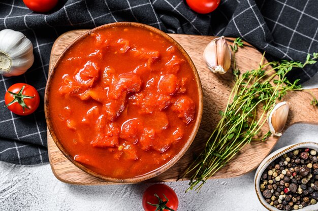 Bowl of chopped tomatoes isolated on rustic white surface. White background. Top view