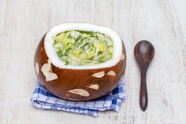 Bowl of coconut with okroshka traditional summer soup