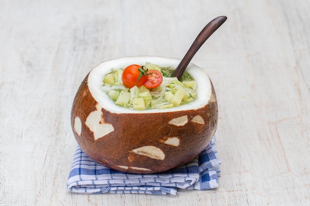 Bowl of coconut with okroshka traditional summer soup