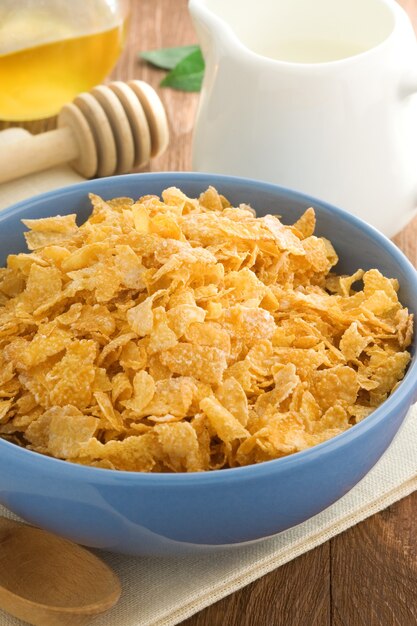 Bowl of corn flakes and milk on wood