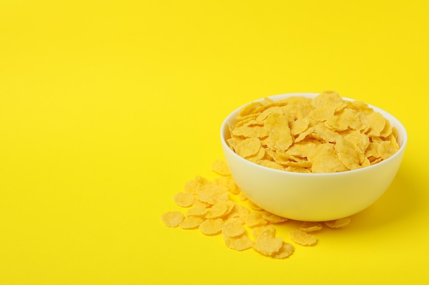 Bowl of corn flakes on yellow background