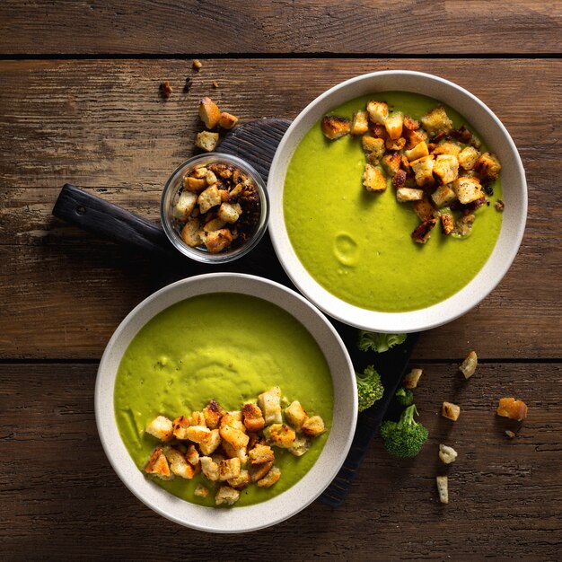 Bowl of cream broccoli soup with bread croutons on a wooden table