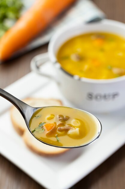 A bowl of delicious brazilian soup with beef, vegetables, noodles, carrots, and potato.