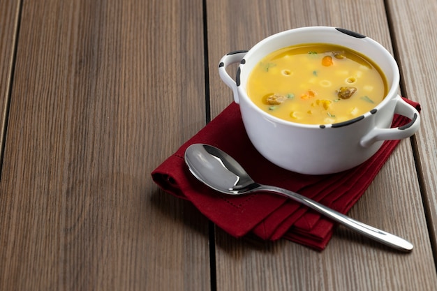 A bowl of delicious brazilian soup with beef, vegetables, noodles, carrots, and potato.