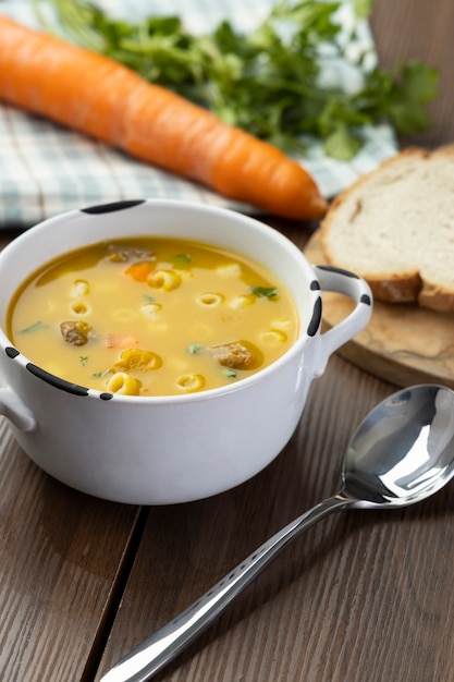 A bowl of delicious brazilian soup with beef, vegetables, noodles, carrots, and potato.