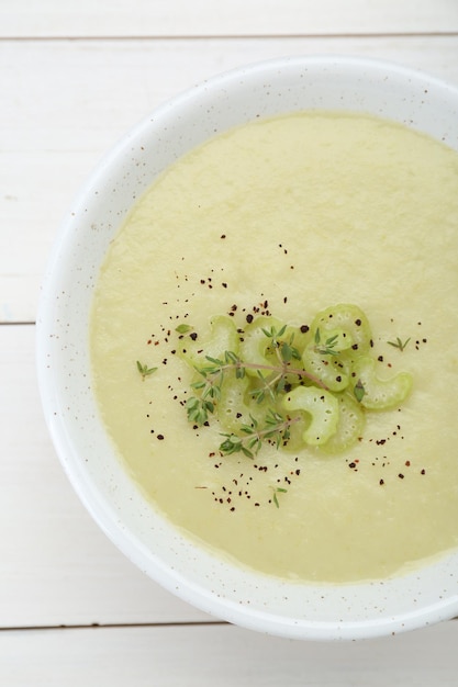 Bowl of delicious celery soup on white wooden table top view