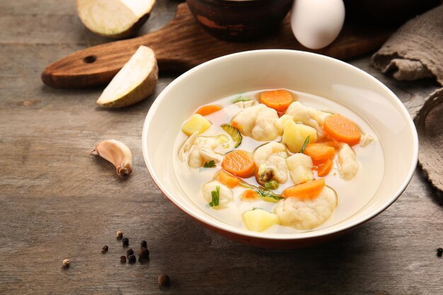 Bowl of delicious chicken and dumplings on wooden dining table