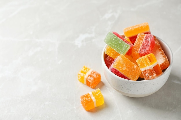 Photo bowl of delicious colorful candies on gray table with space for text