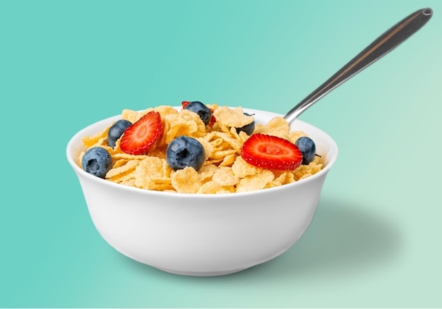 Bowl of delicious cornflakes on mint background