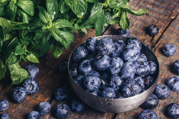 Bowl of delicious fresh blueberries with green leaves