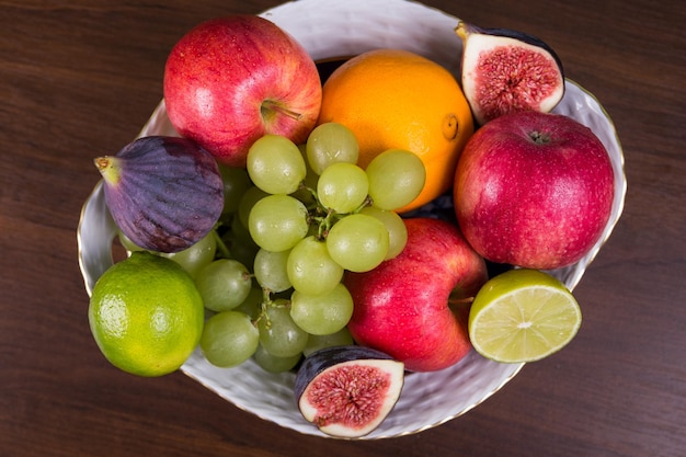 Bowl of different fruits on wooden table