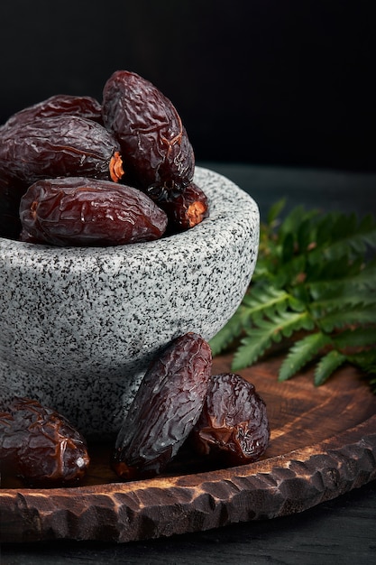 Bowl of dried dates on dark wooden table