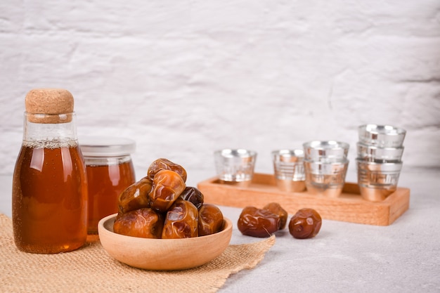 Photo bowl of dried dates fruit and honey on a white concrete background copyspace