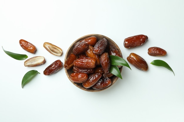 Bowl of dried dates with leaves on white