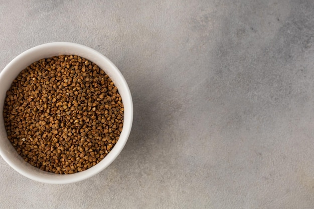 Foto una ciotola di grano saraceno secco prima della cottura su uno sfondo grigio chiaro