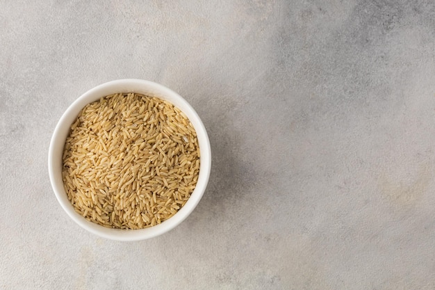 Bowl of dry long grain white rice on a light background