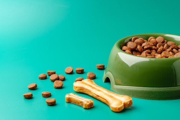 Bowl of dry pet food on green background