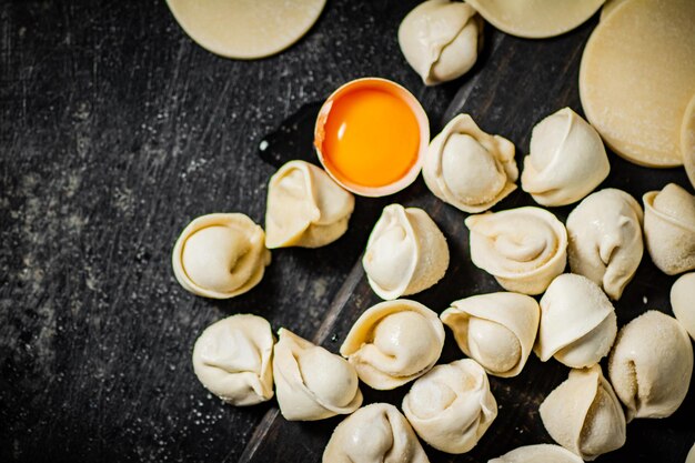 A bowl of dumplings with a cup of sauce on the side