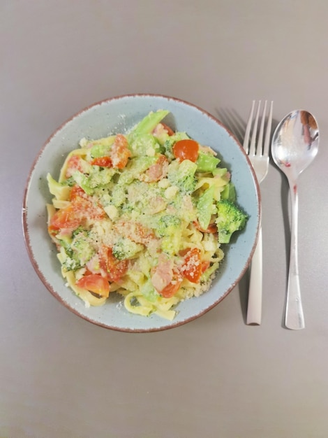 A bowl of food with a fork next to it and a fork.