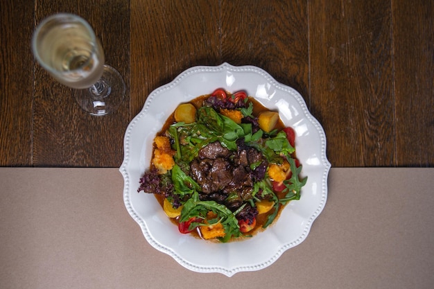 a bowl of food with a glass of wine next to it