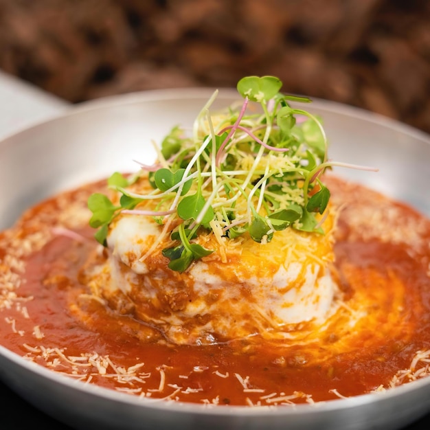 A bowl of food with a tomato sauce and sprouts on top.