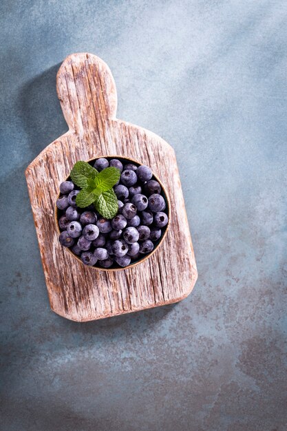 Bowl of fresh blueberries on rustic wooden board