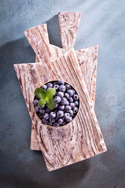 Photo bowl of fresh blueberries on rustic wooden board