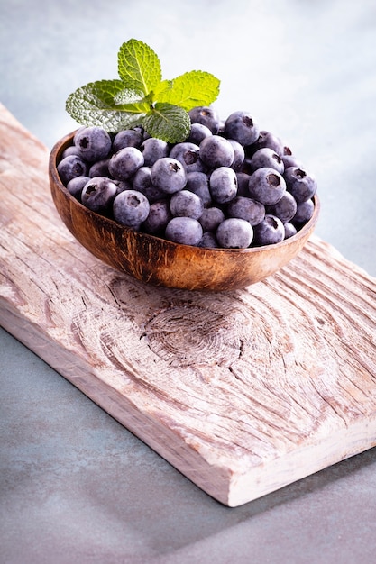 Bowl of fresh blueberries on rustic wooden board