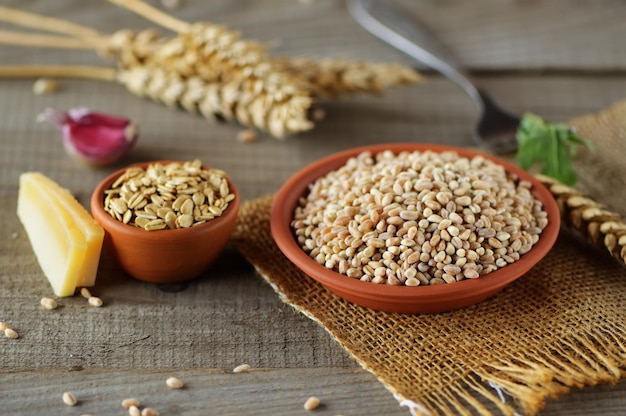 A bowl of fresh grain on a wooden backgroundEar of wheat