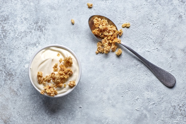 Bowl of fresh greek yogurt with muesli on kitchen table, top view