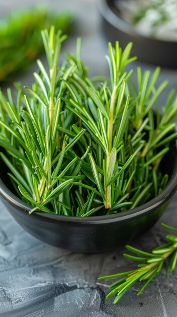 A bowl of fresh green herbs including rosemary is sitting on a counter