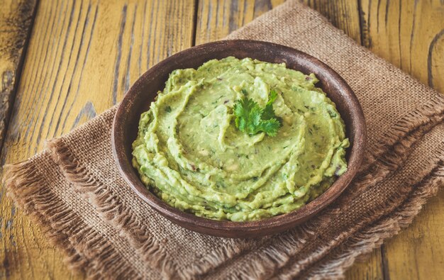 Bowl of fresh guacamole on rustic background