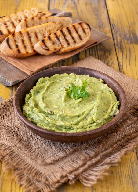 Bowl of fresh guacamole on rustic background