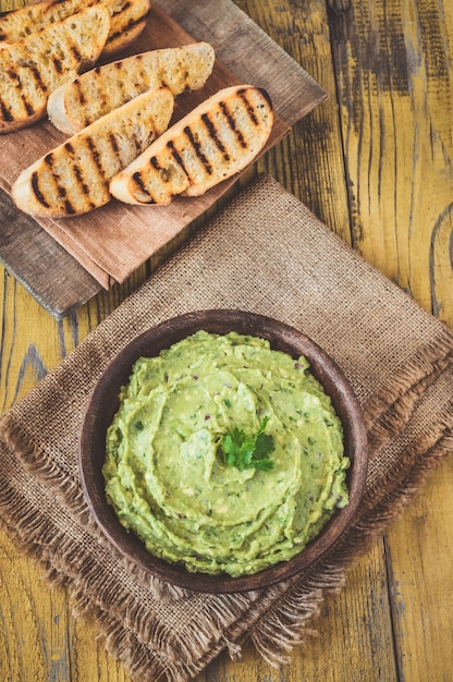 Bowl of fresh guacamole on rustic background