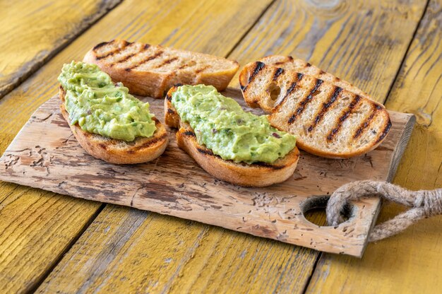 Photo bowl of fresh guacamole on rustic background