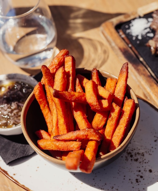 A bowl of fries with a glass of water on the side.