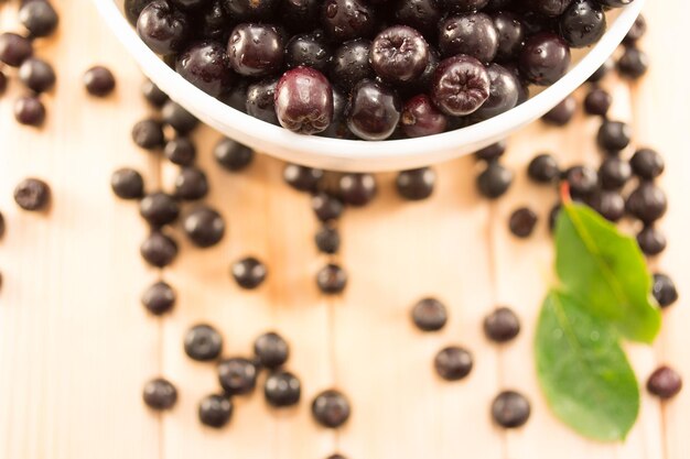 Photo bowl full of aronia spilled on wooden table