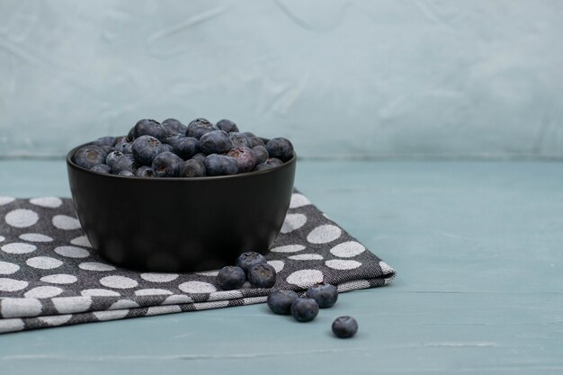 Bowl full of blueberries on mint stone background. Fresh berries.