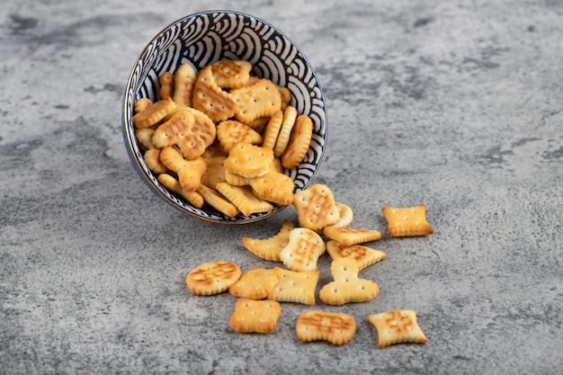 Bowl full of crispy crackers placed on a stone background . 