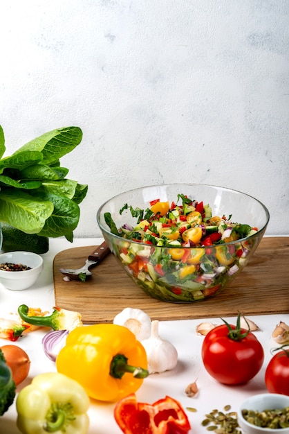 Ciotola piena di insalata di diverse verdure eco con ingredienti e spezie sul tavolo